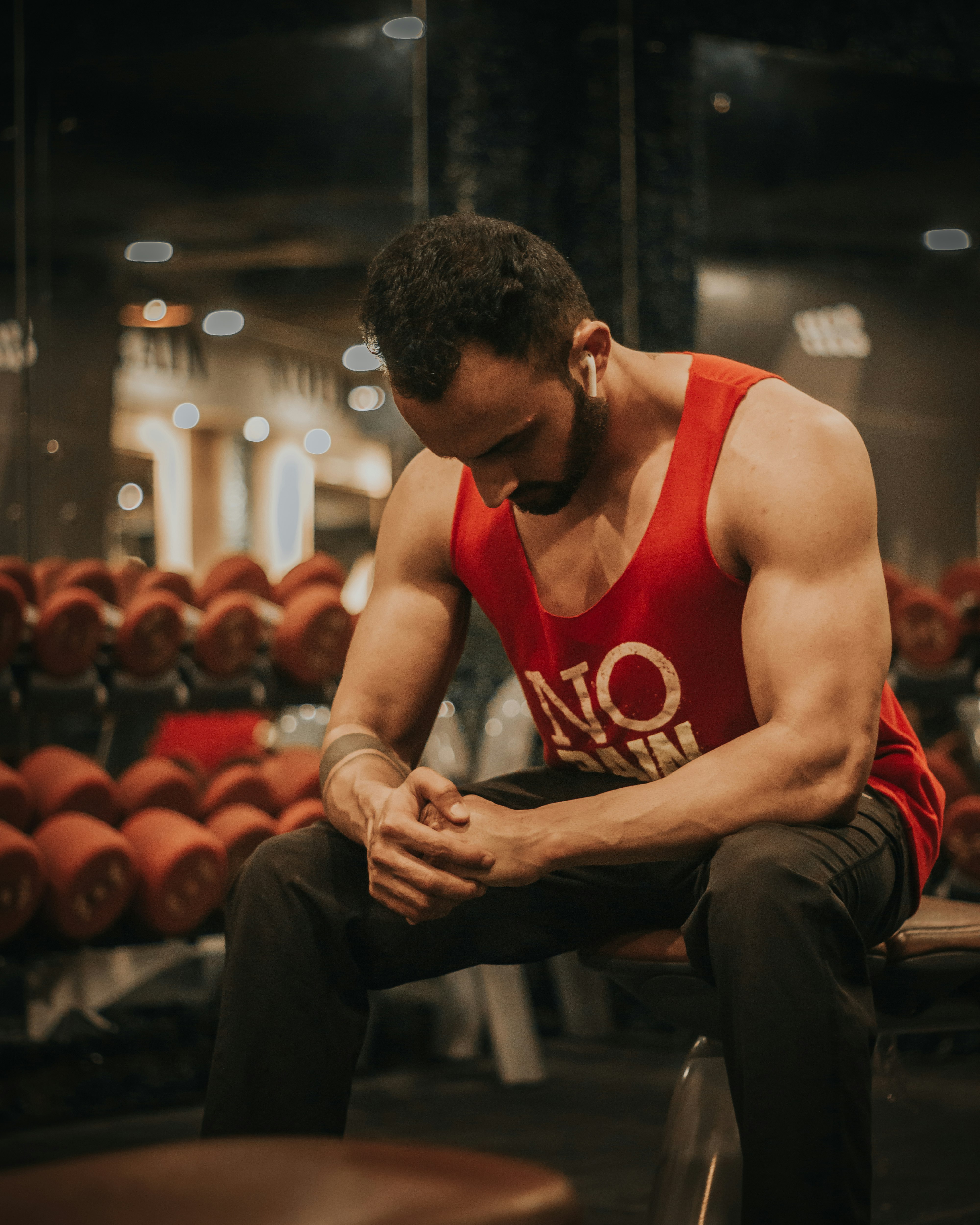 man in red tank top and black pants sitting on chair